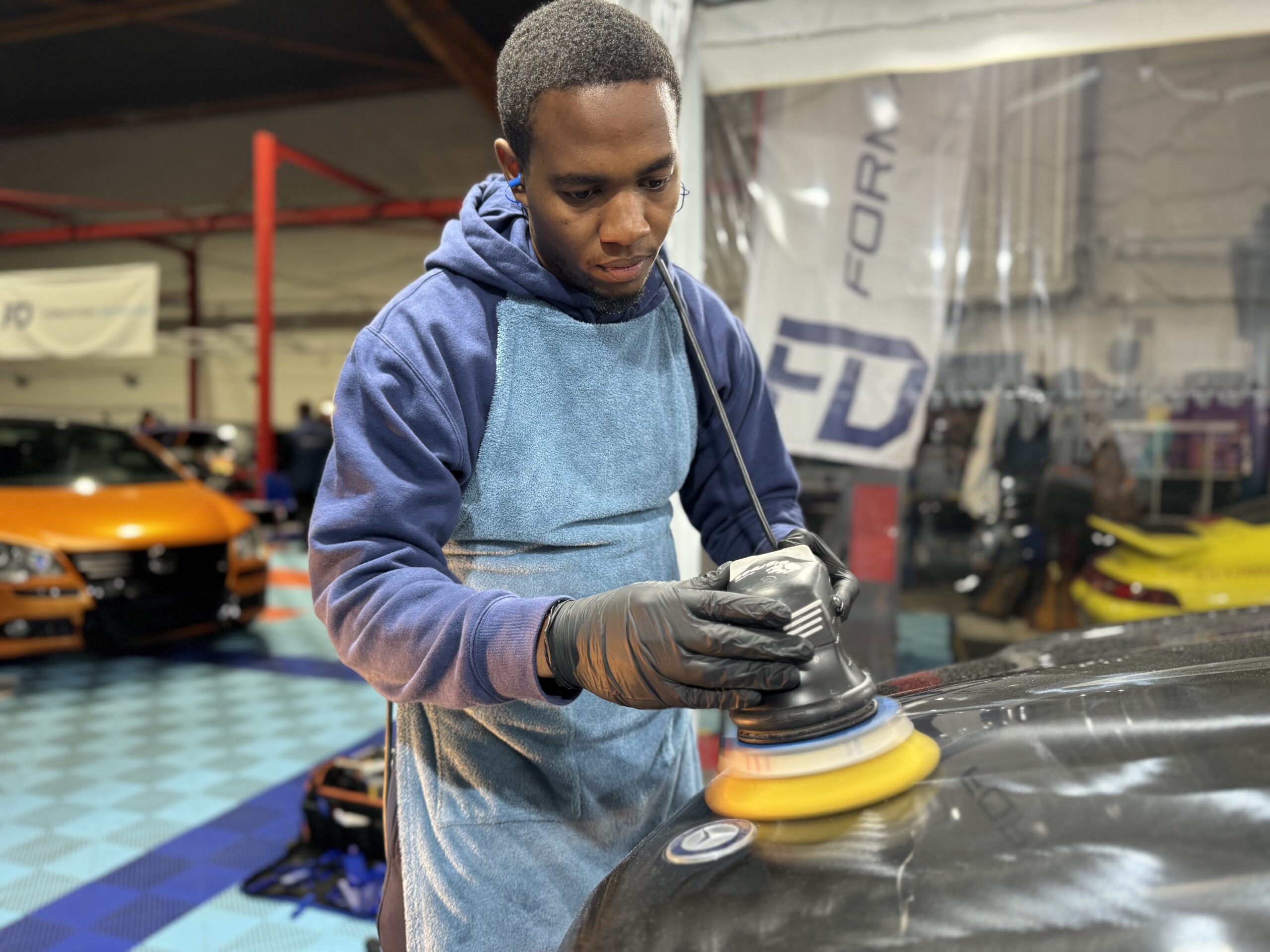 Stagiaire en tablier polissant une carrosserie