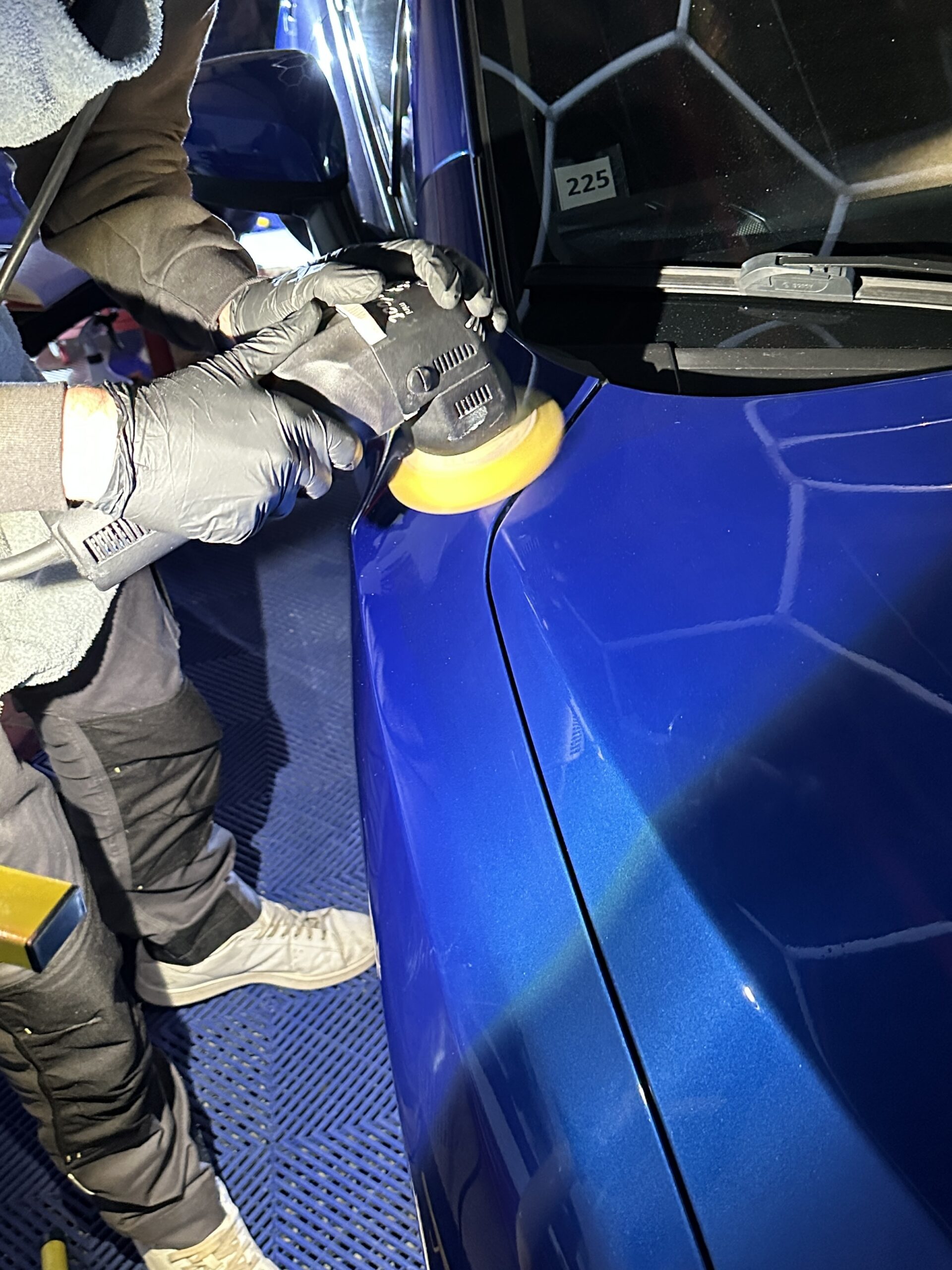 Stagiaire polissant une carrosserie bleue